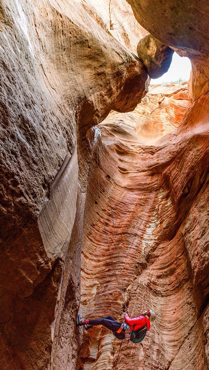 A person is climbing up a rock wall in a canyon.