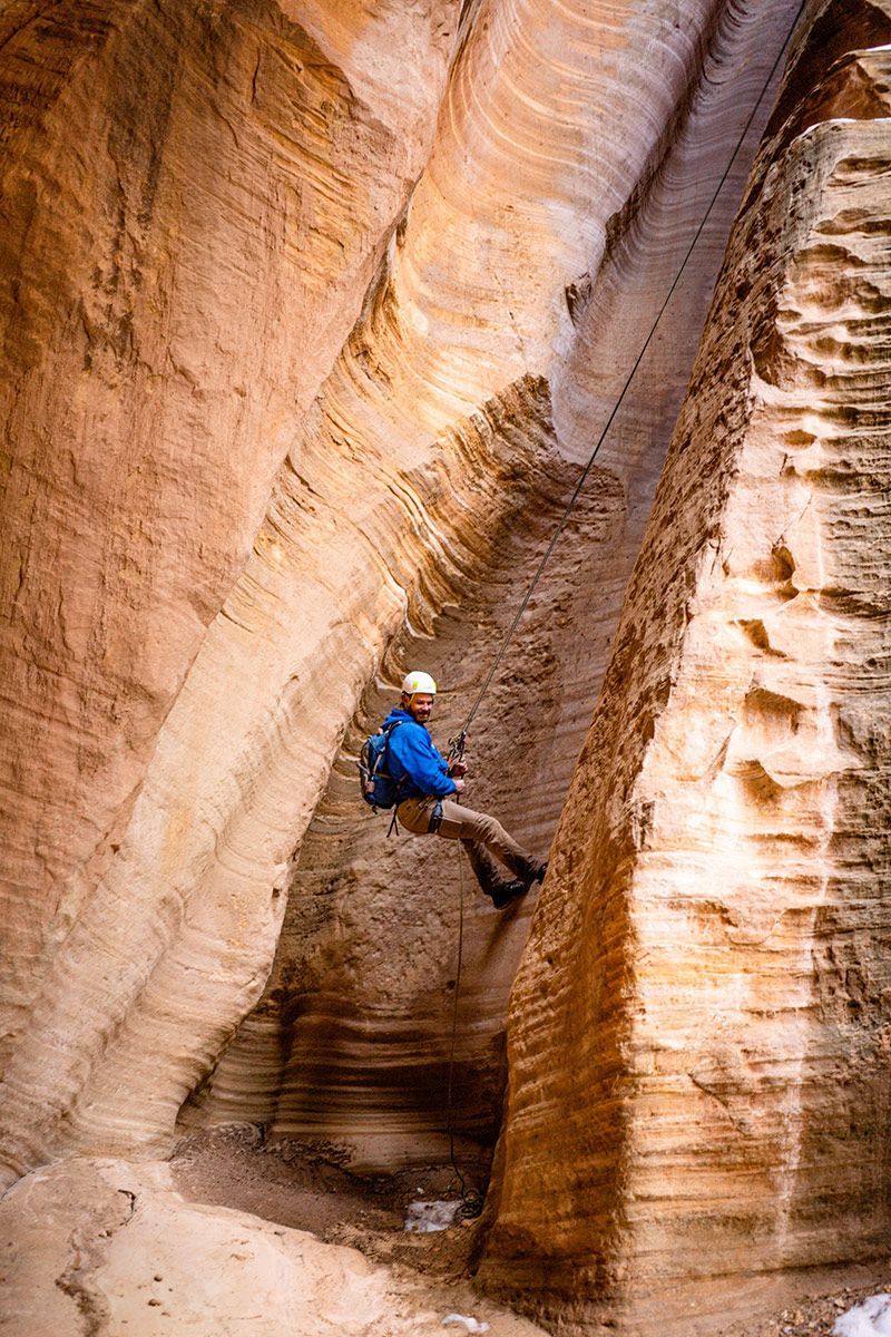 A person is hanging from a rope in a canyon.