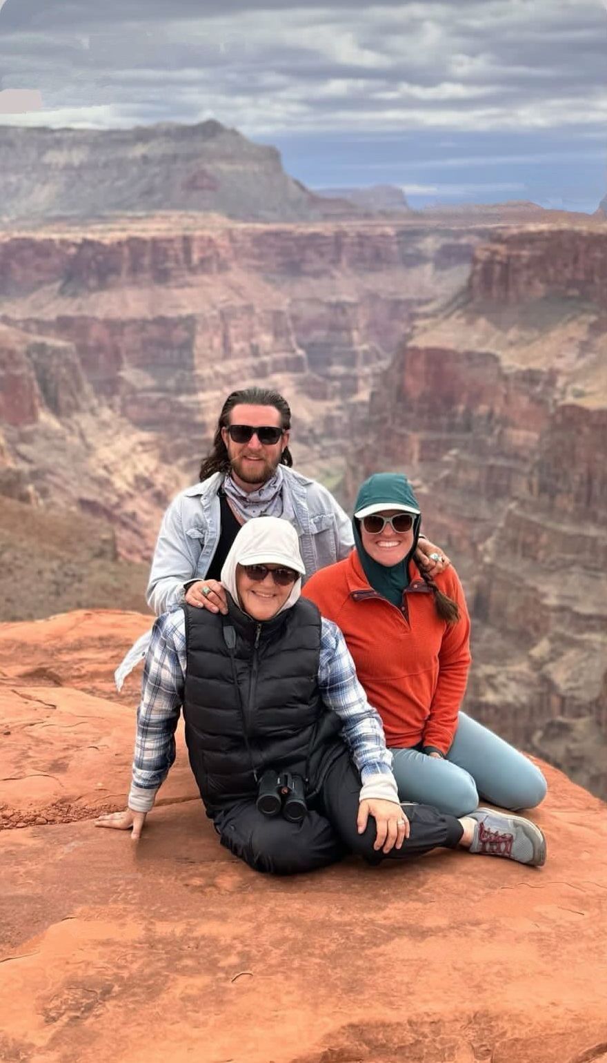 A group of people are posing for a picture on the edge of a canyon