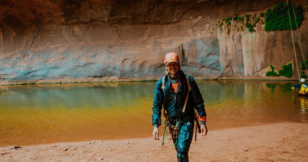 A man is walking across a sandy beach next to a body of water.