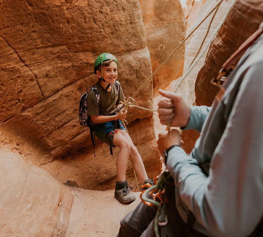 A man and a boy are sitting on a rock in a canyon.