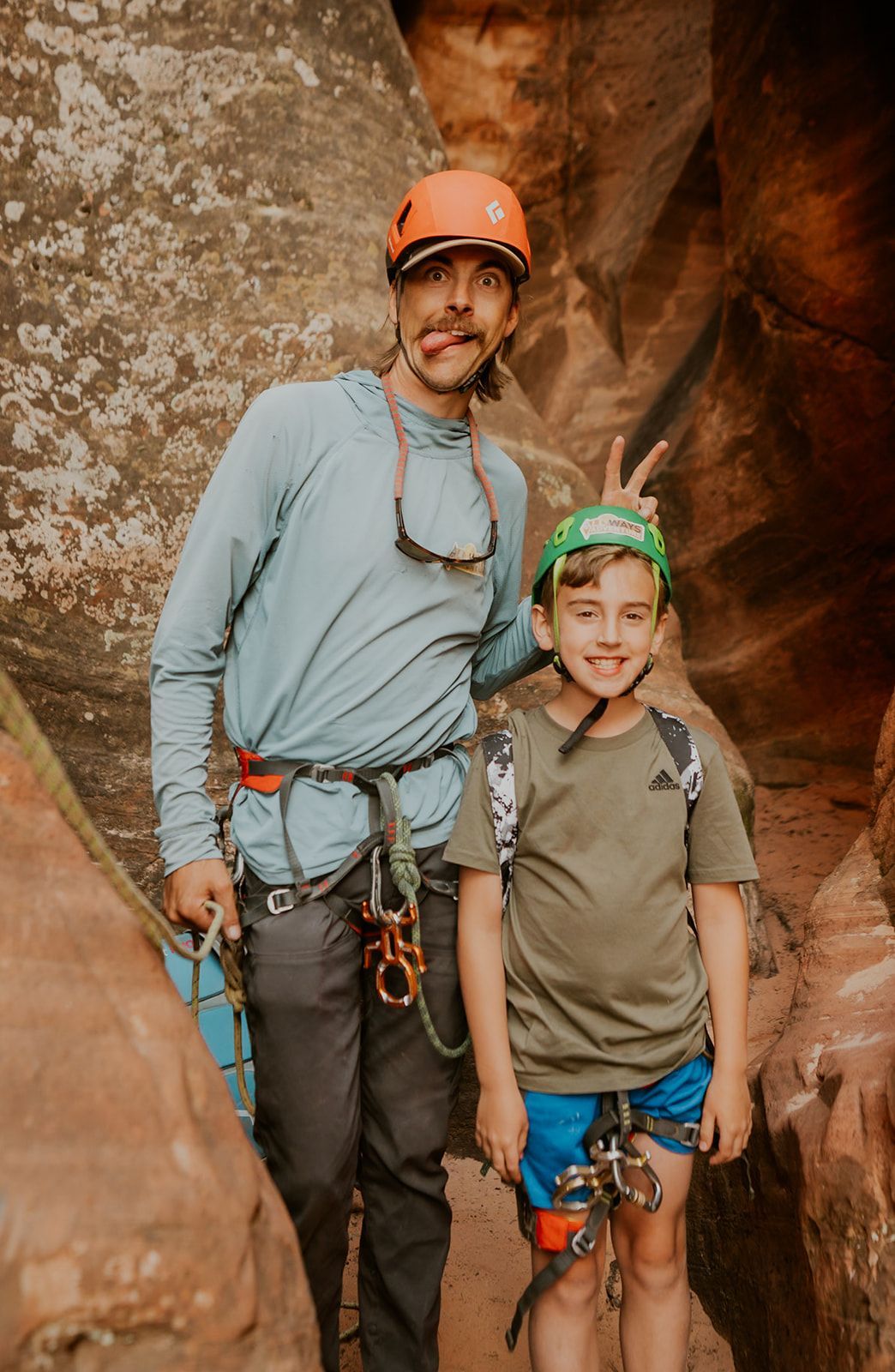 Nathan is posing with a kid and doing bunny ears with his fingers