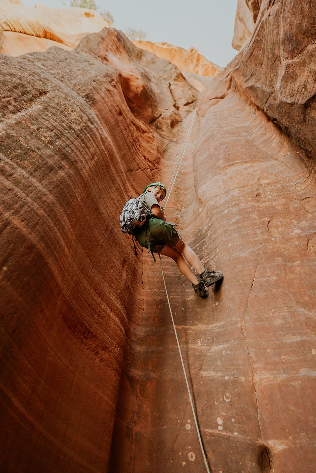 A person is climbing up a rock wall with a rope