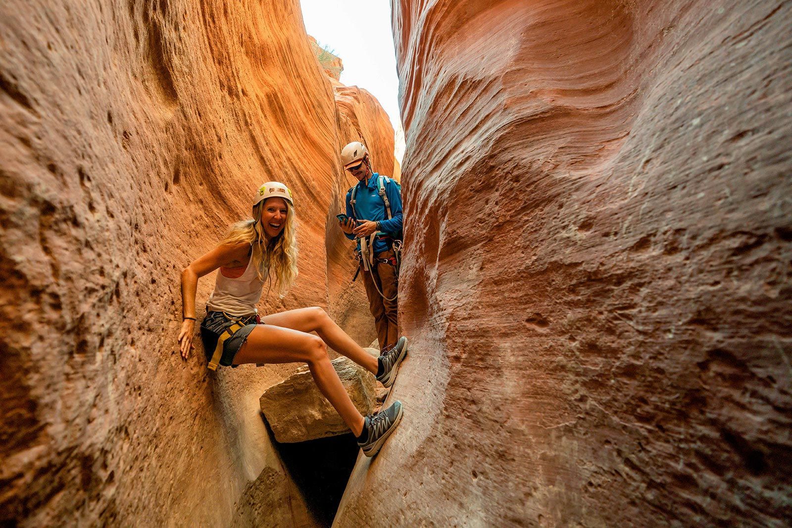 A man and a woman are hiking through a canyon