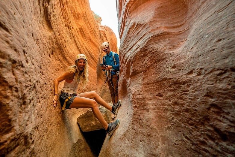 A woman climbing while in a narrow slot canyon