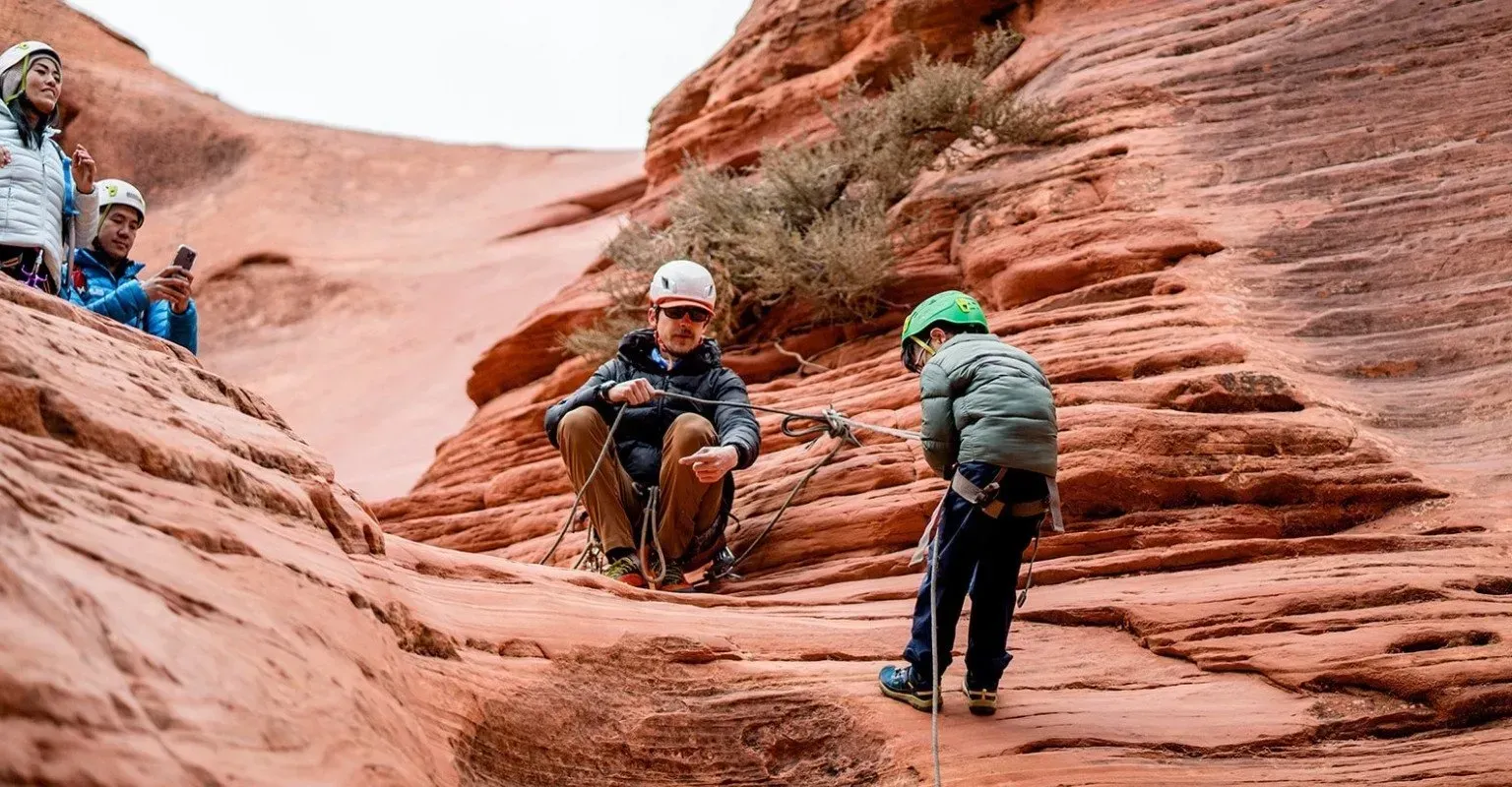 A man and a child are climbing up a rock wall.