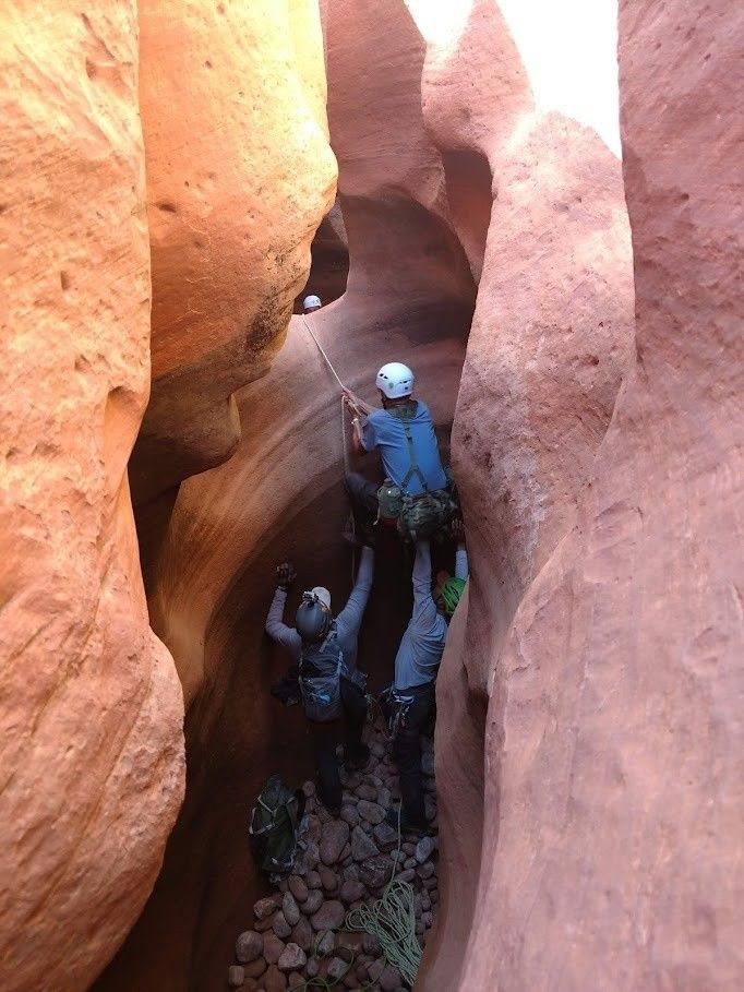 A group of people are walking through a canyon.