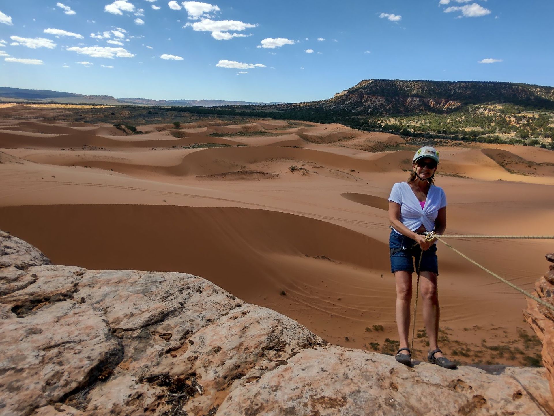 A woman is standing on top of a rock in the desert.