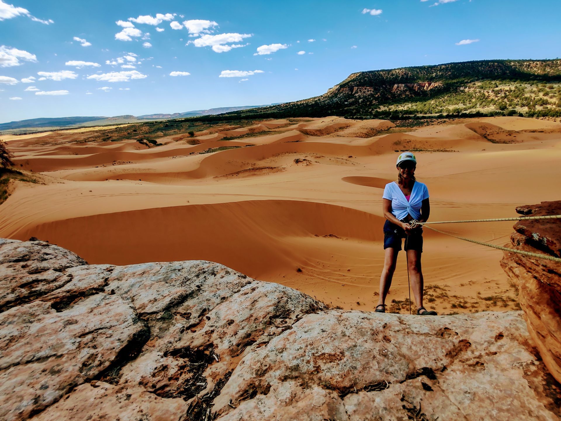 A woman in a helmet is holding onto a rope while climbing a mountain.