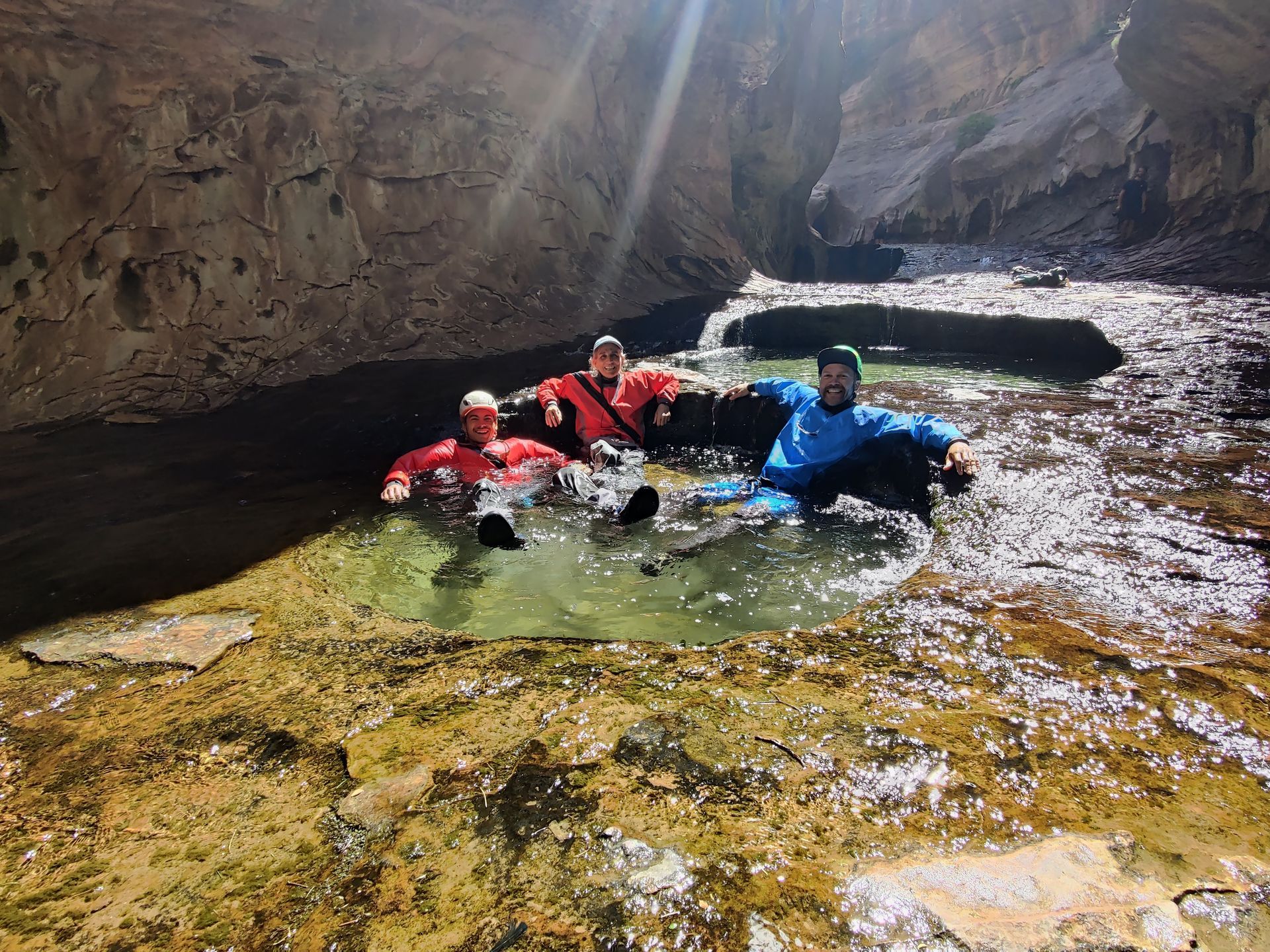 Nathan, Brett and a friend are relaxing in a pool of water while wearing drysuits