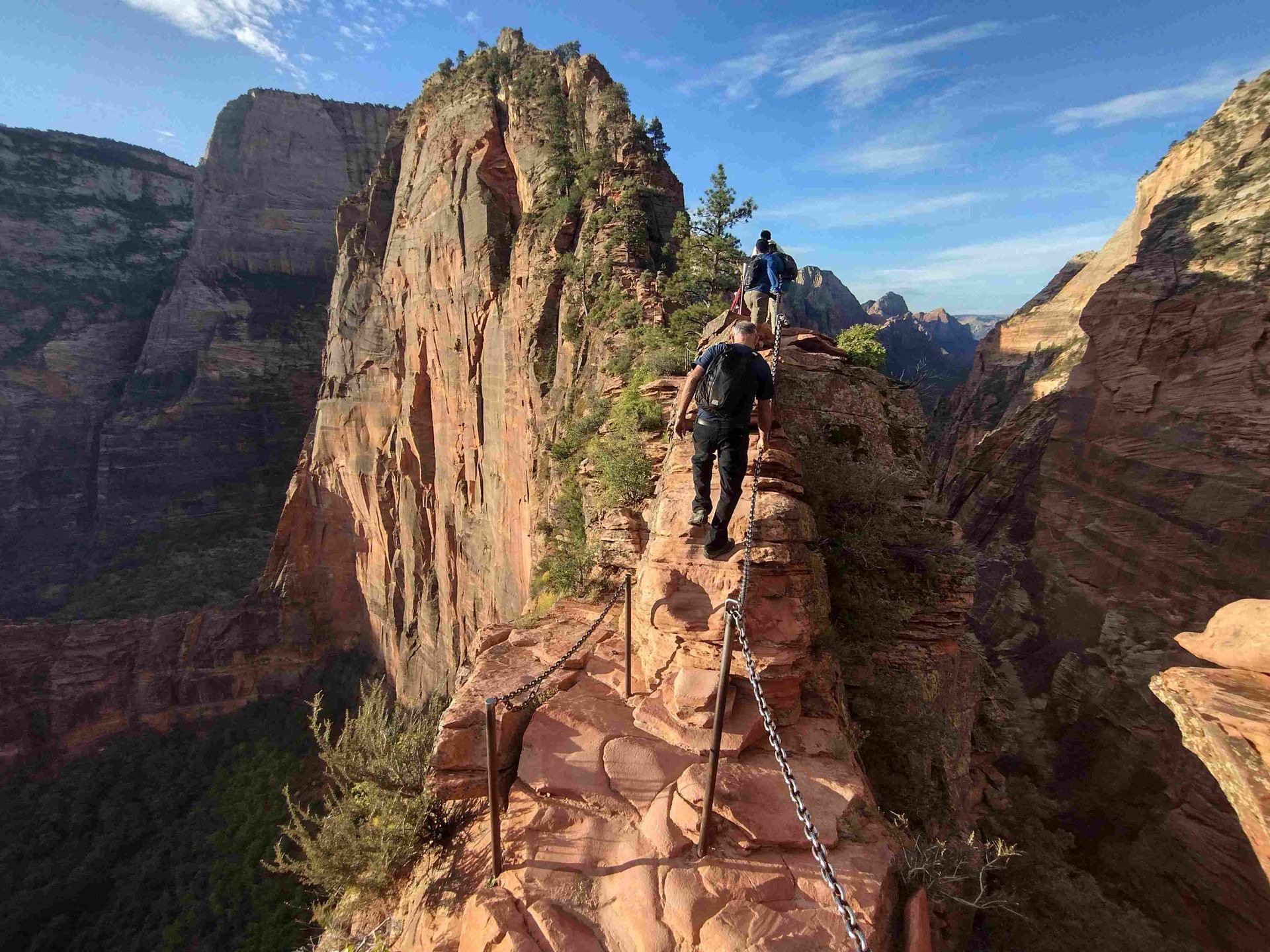 A group of people are hiking up a cliff on a chain.