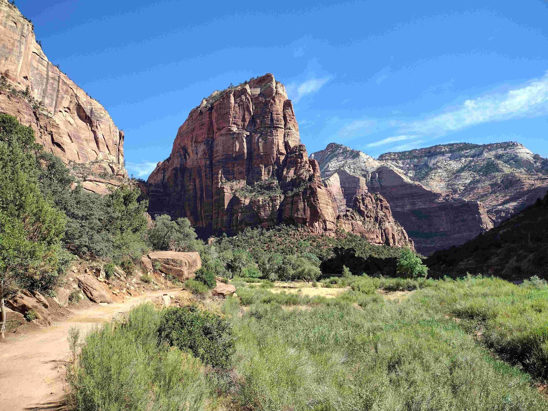 A dirt road going through a valley with mountains in the background