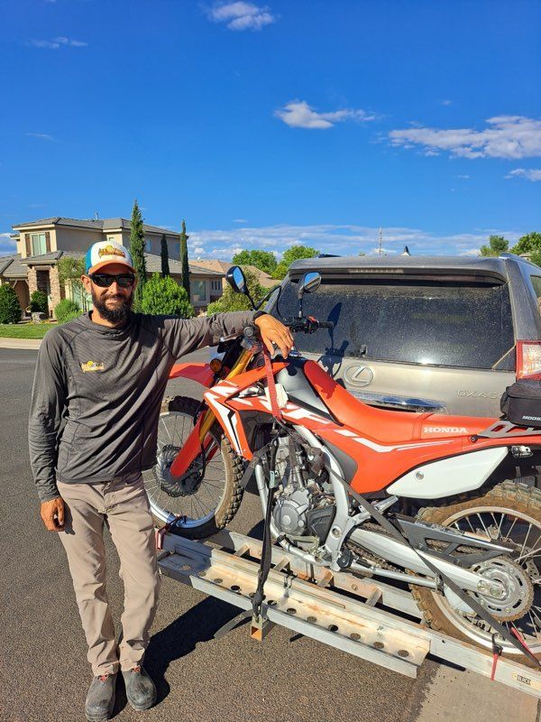 Darren is posing with his dirtbike on a rack on the back of his landcruiser
