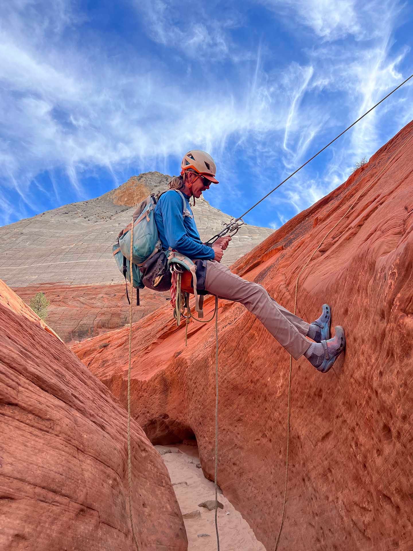 A person is sitting on a rock with their feet on a rope.