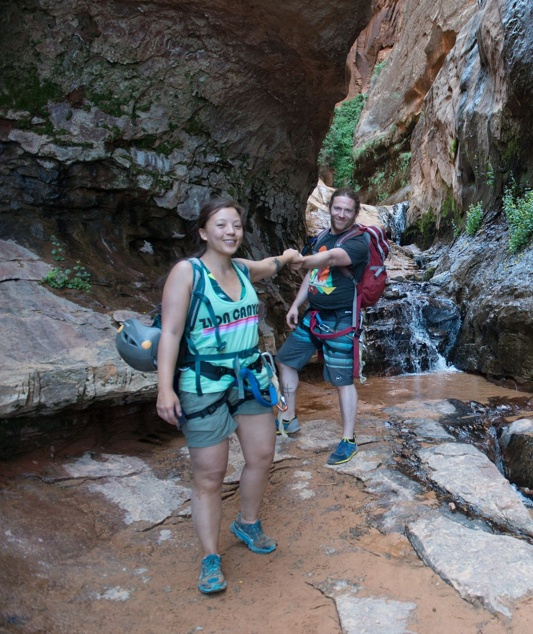 Two people hold hands in a canyon