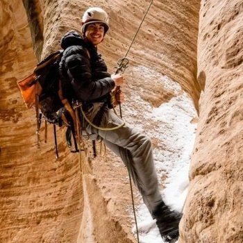 A man wearing a helmet is climbing up a rock wall.