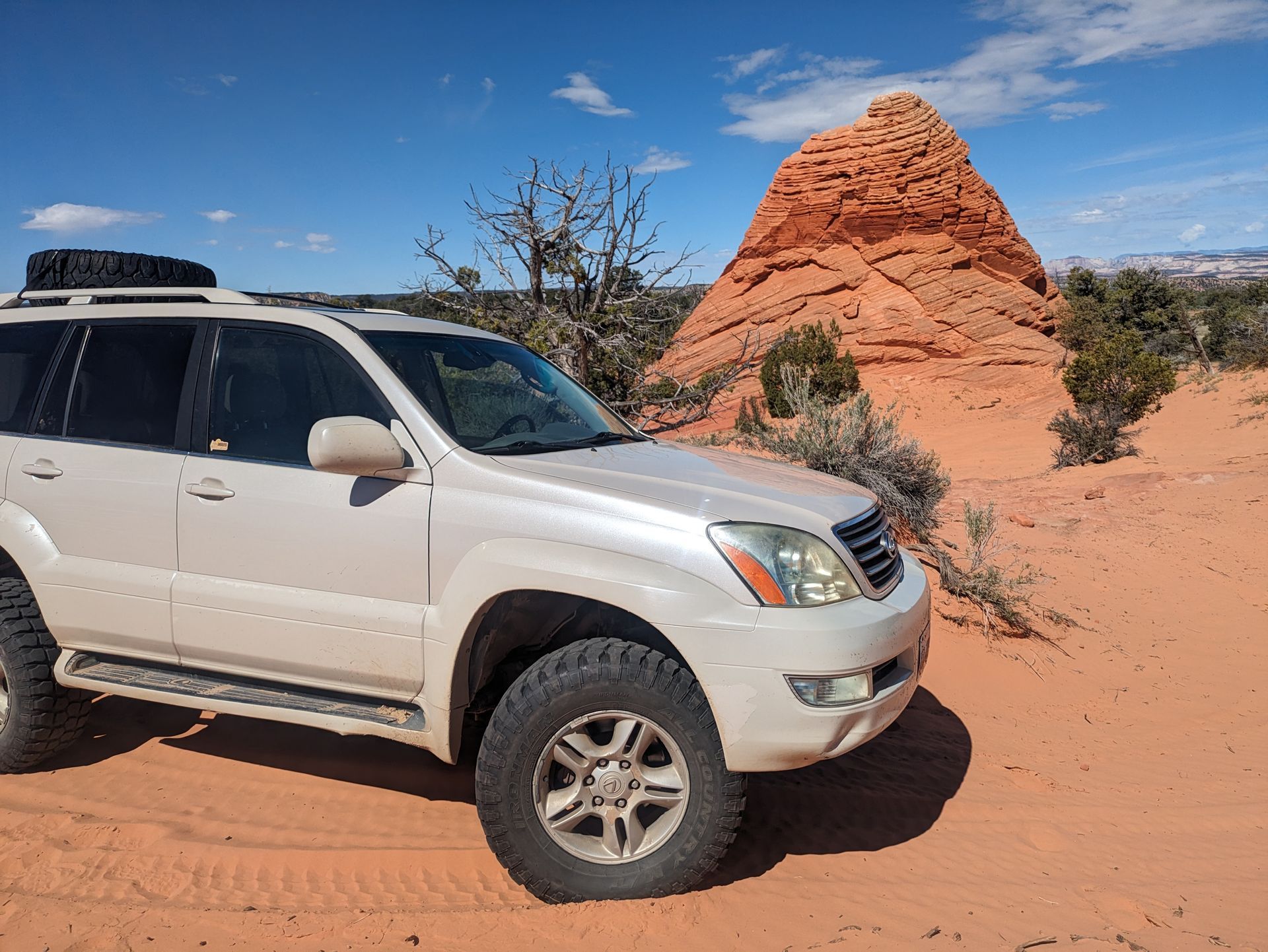 A white SUV with a red rock tower in view