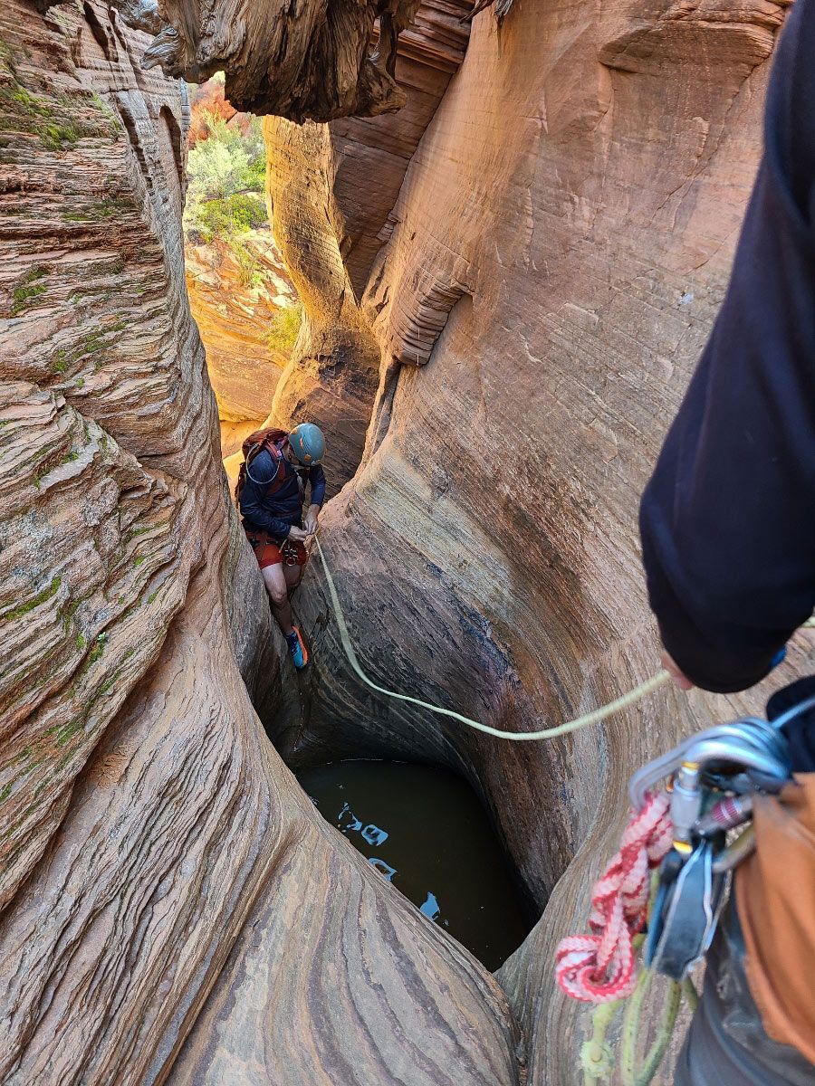 A rope is dangling over a pothole filled with water.