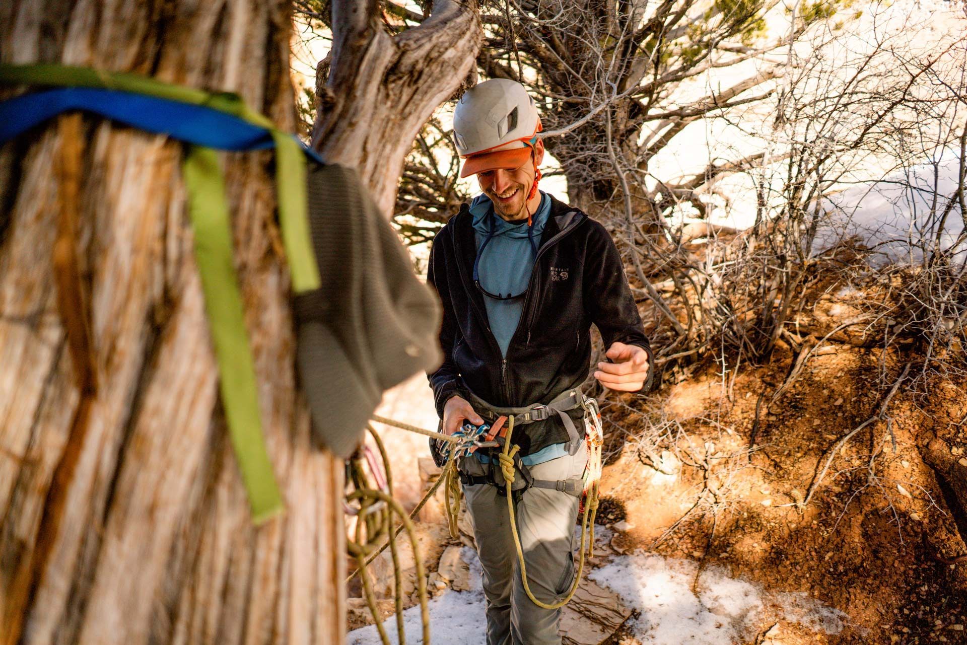 A man wearing a helmet is standing next to a tree.