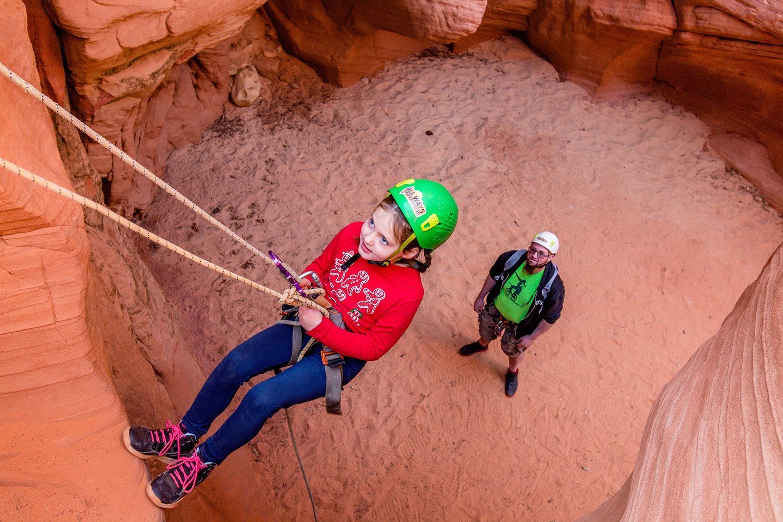 A woman in a blue jacket is holding onto a rope in a canyon