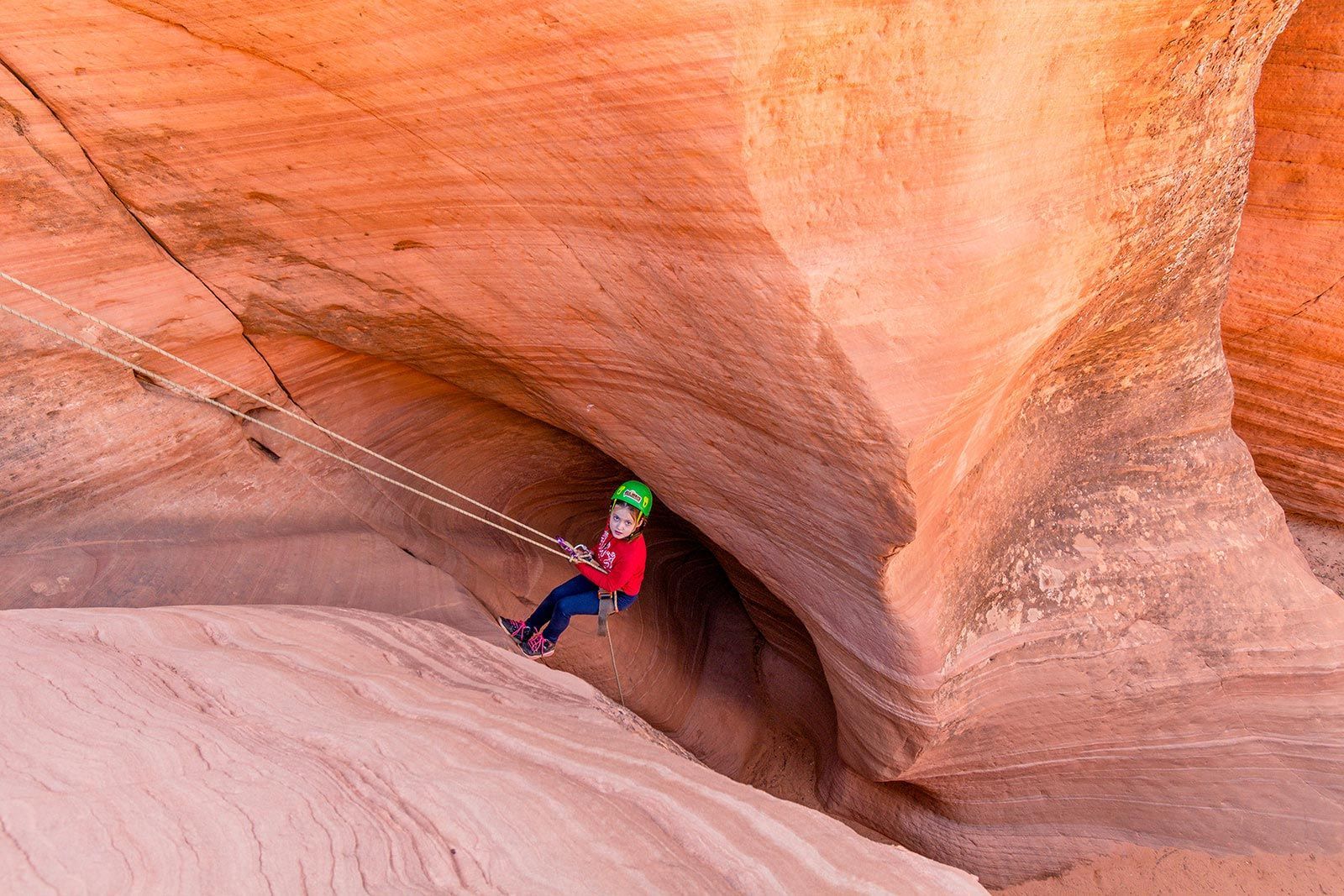 A young boy is hanging from a rope in a canyon