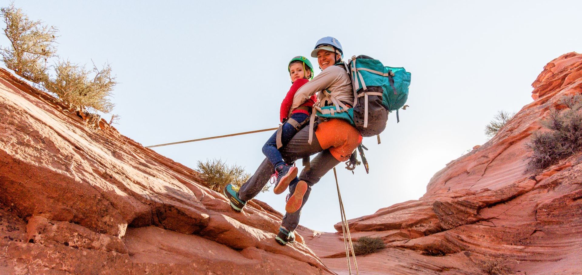 A man and a child are climbing up a rock wall.