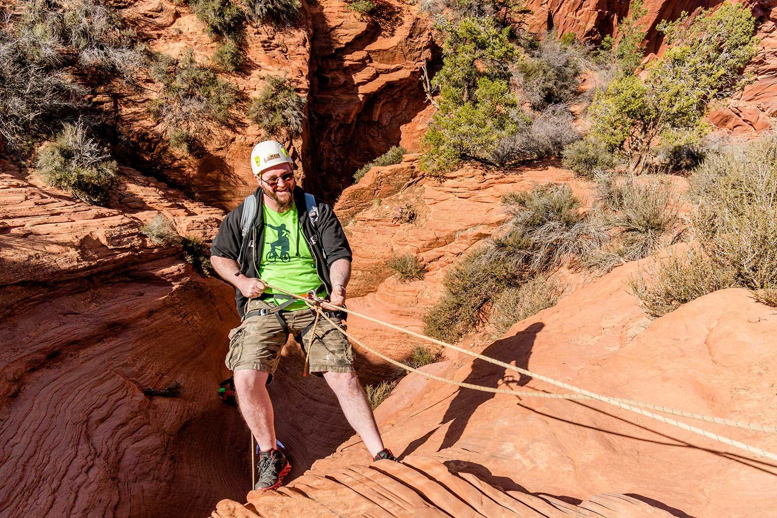 a man rappelling down a canyon