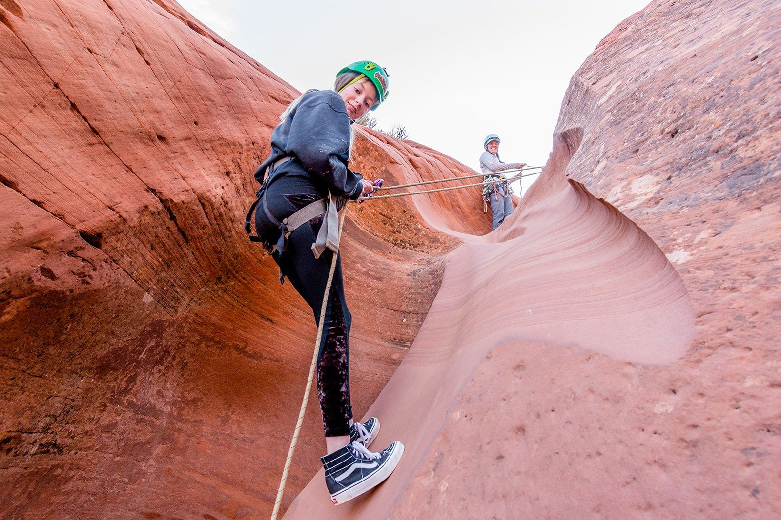 A person is climbing up a rock wall with a rope.