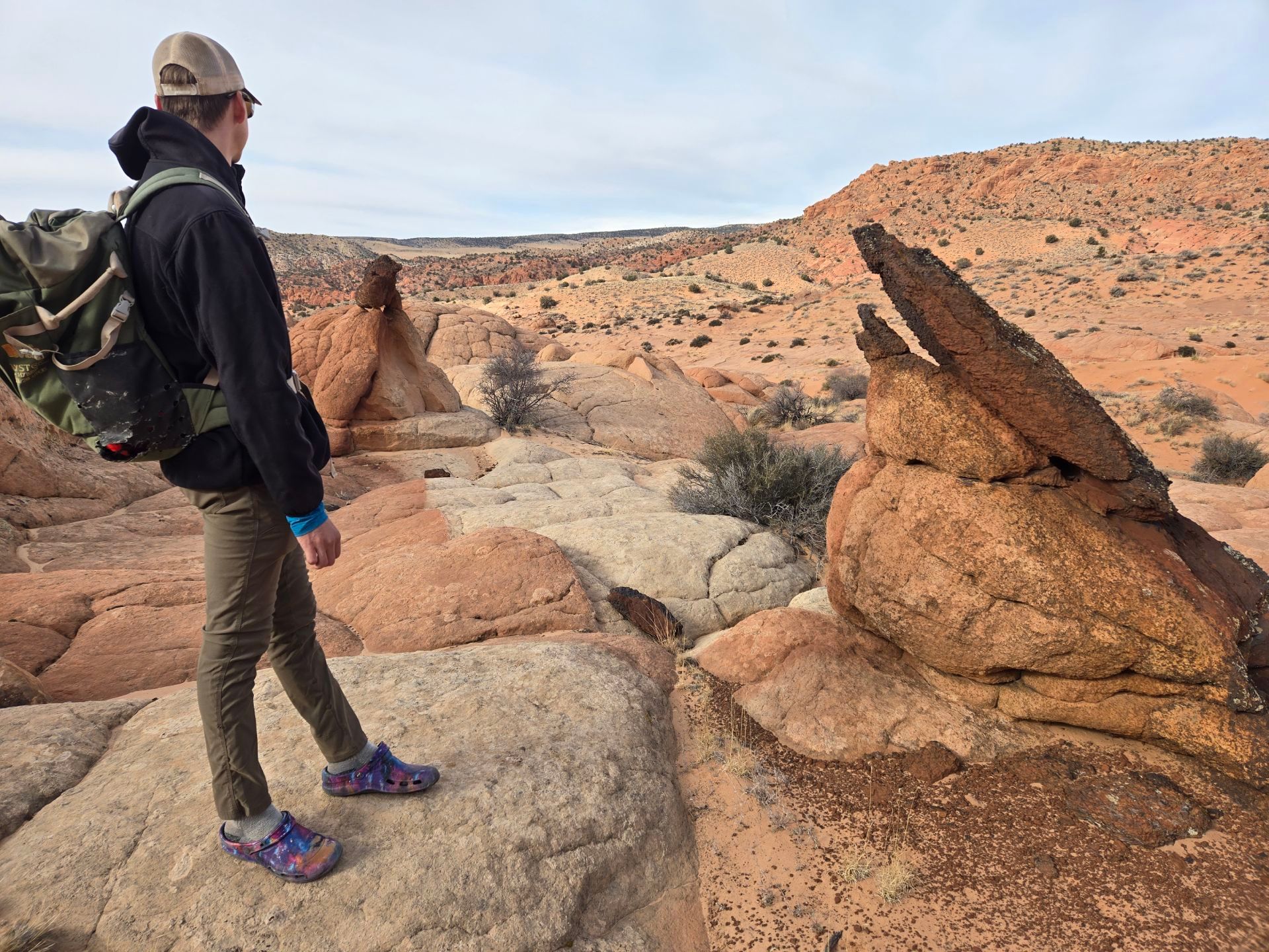A person looks at a sandstone formation under the bright blue sky