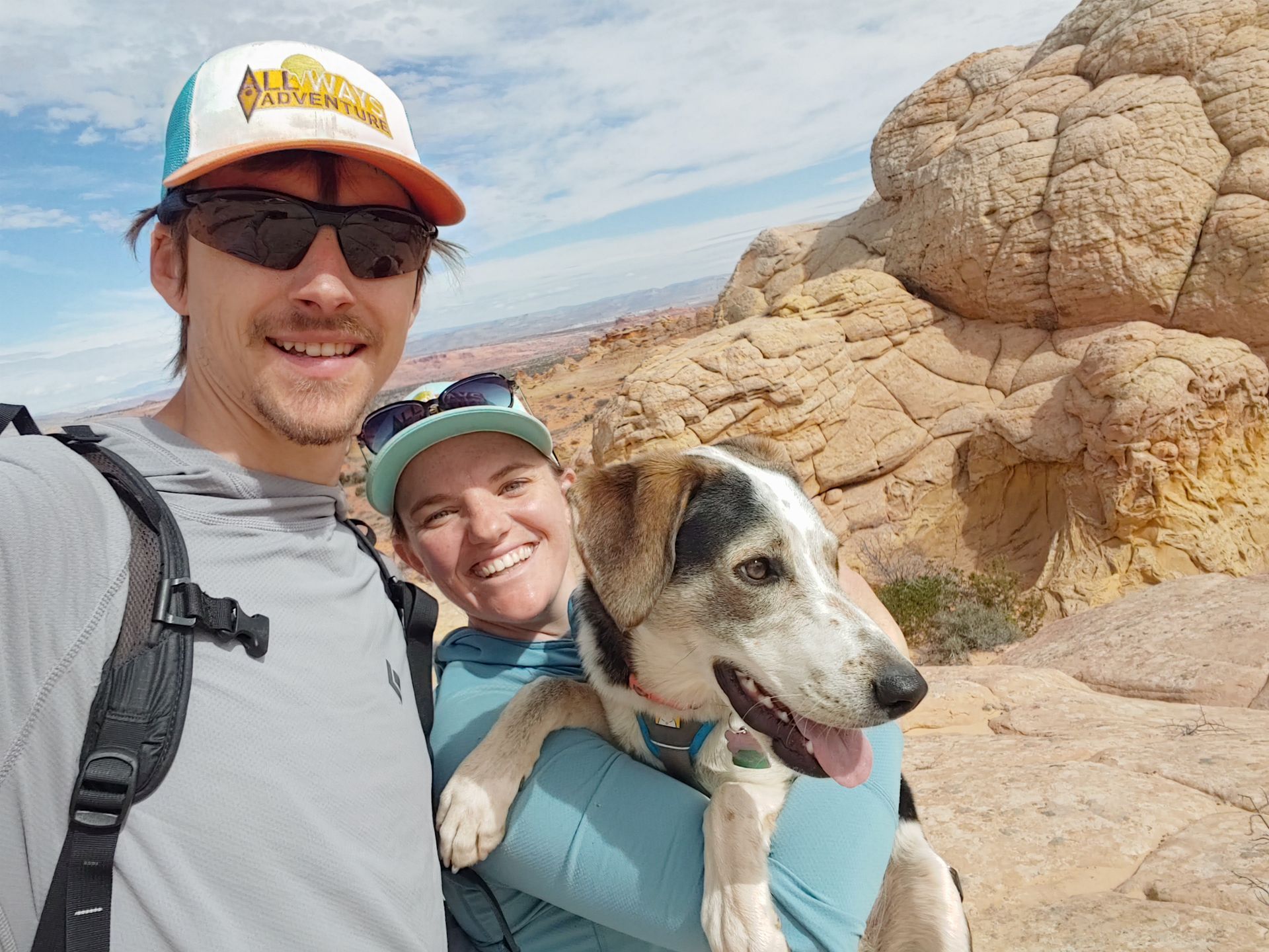 A man and a woman are holding a dog in their arms.