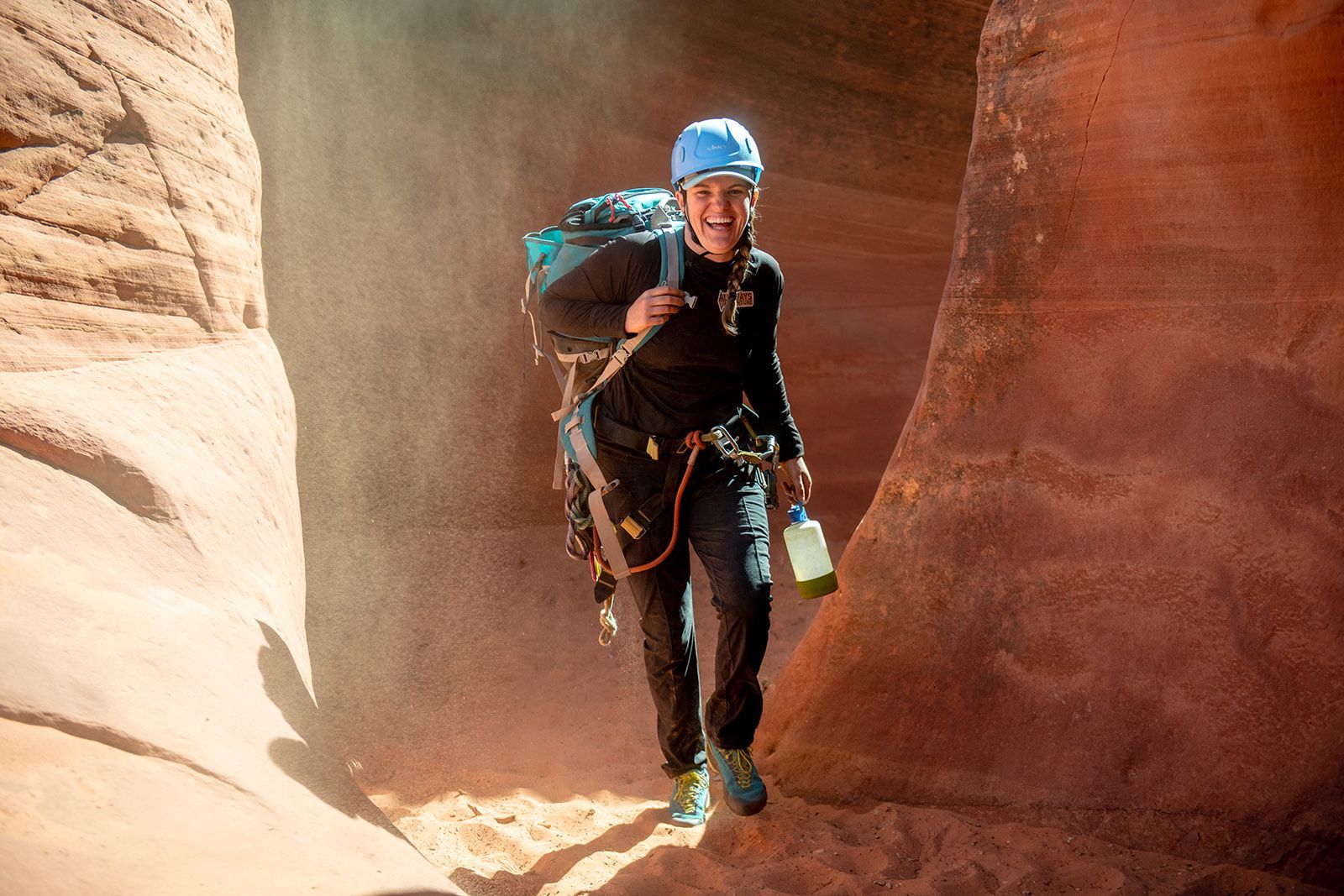 Jillian is carrying a large backpack and walking through a canyon. 