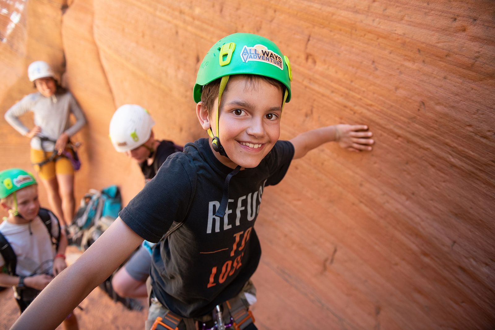 A young boy wearing a green helmet and a shirt that says refuse to lose