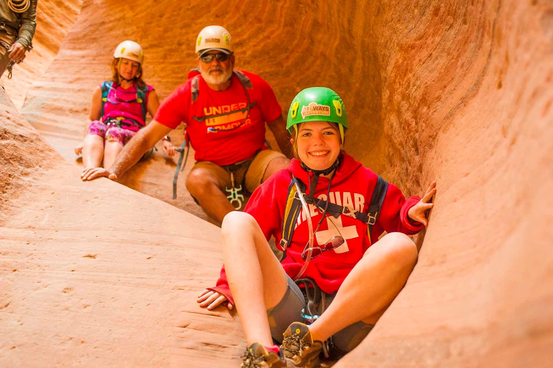 A man wearing a red shirt that says sunday is sitting next to a girl wearing a green helmet