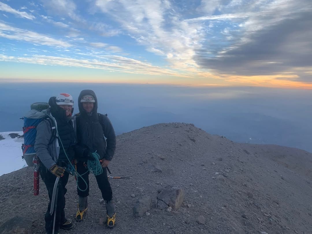 Two people standing at the summit of a mountain