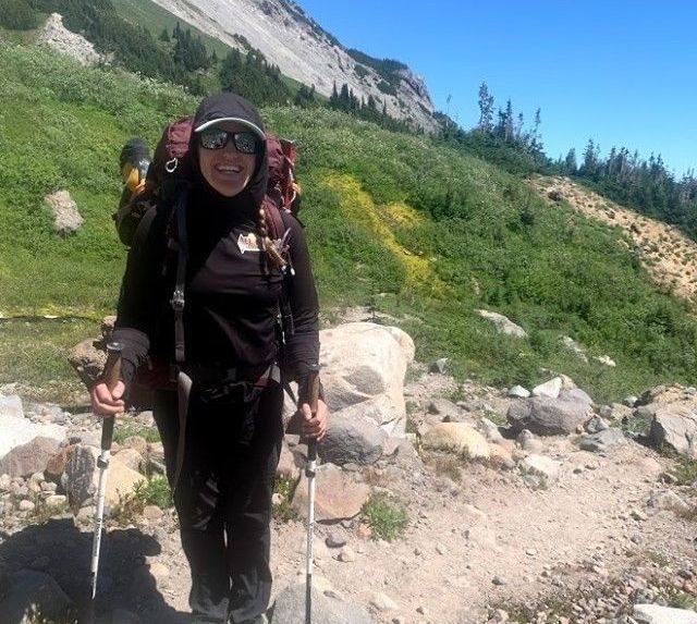 A person smiles while wearing a hiking backpack