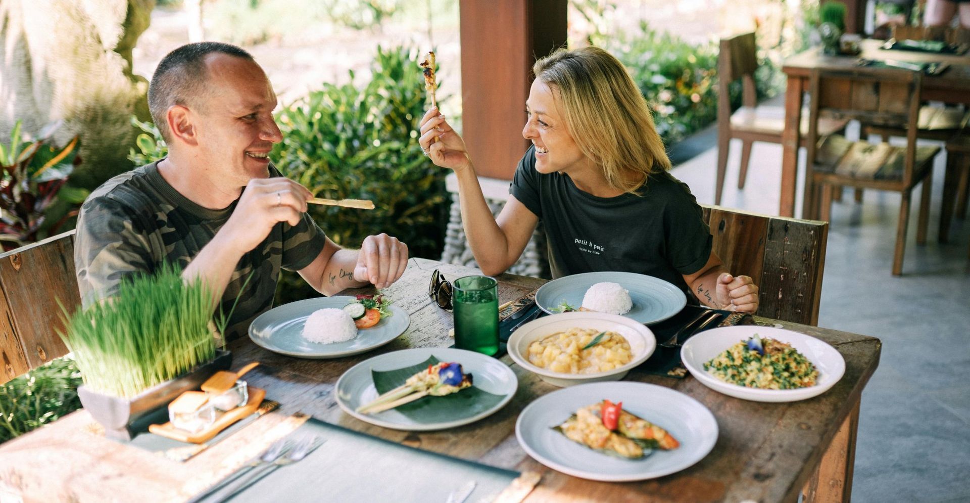 A man and a woman are sitting at a table with plates of food.