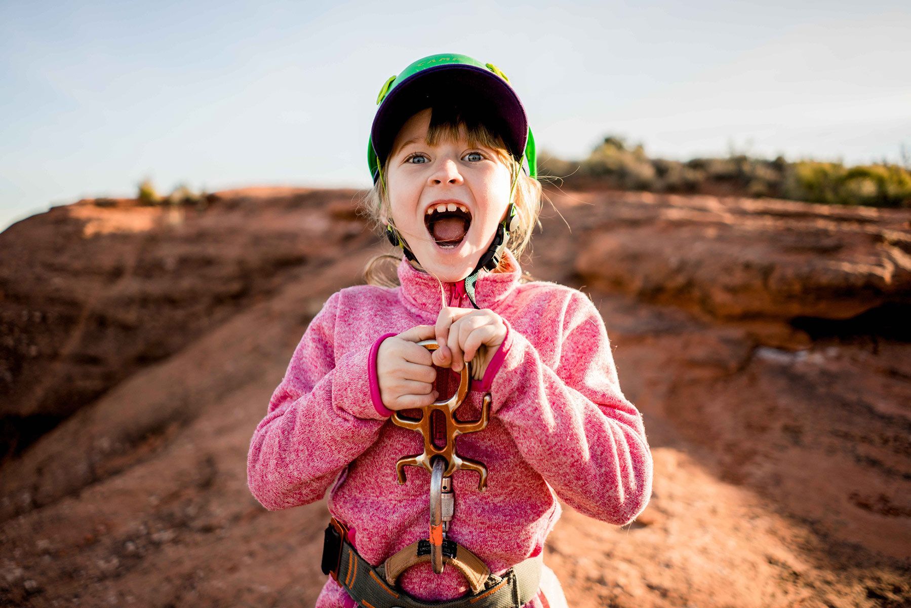 A little girl is wearing a helmet and holding a rope