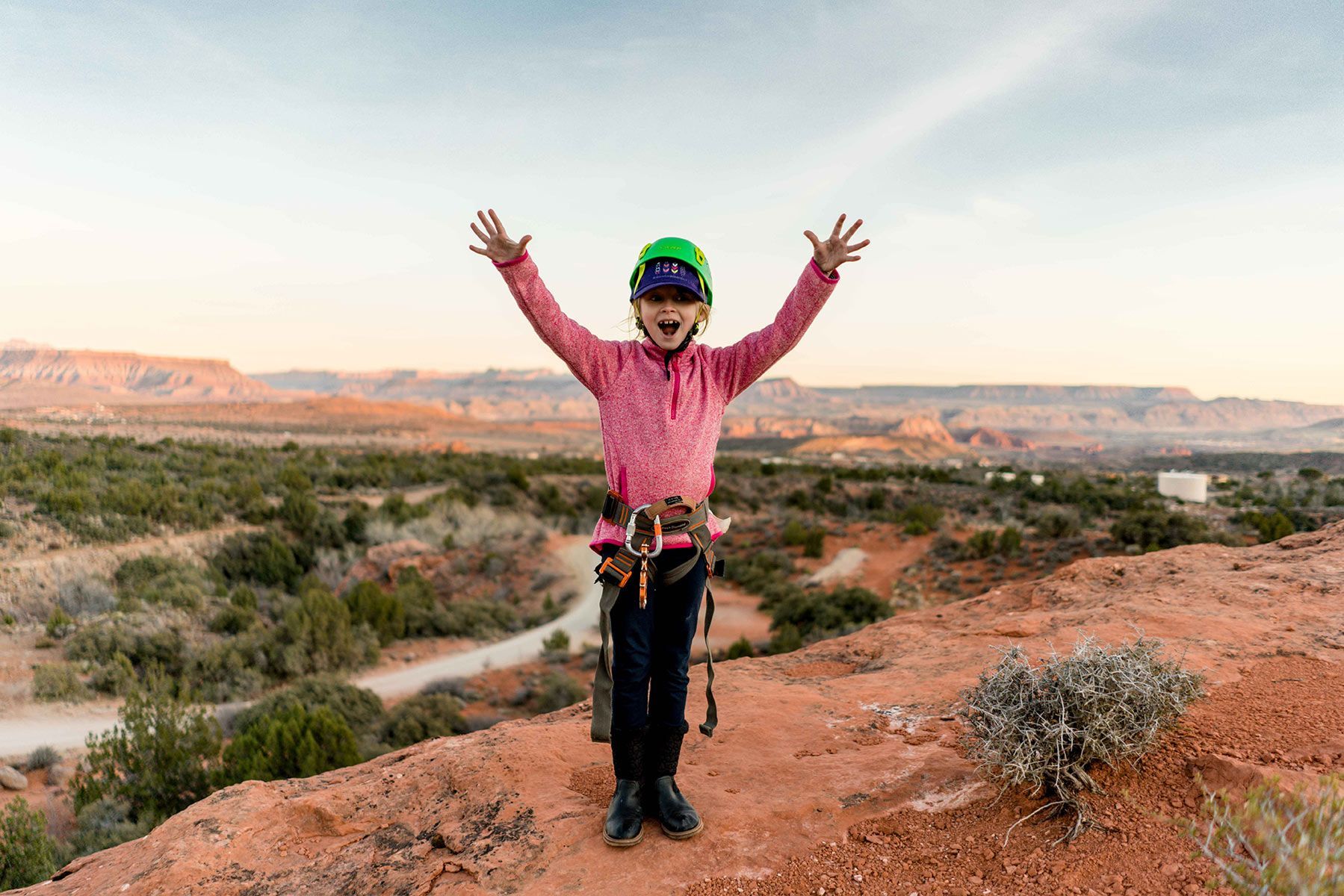 A young girl is standing on top of a mountain