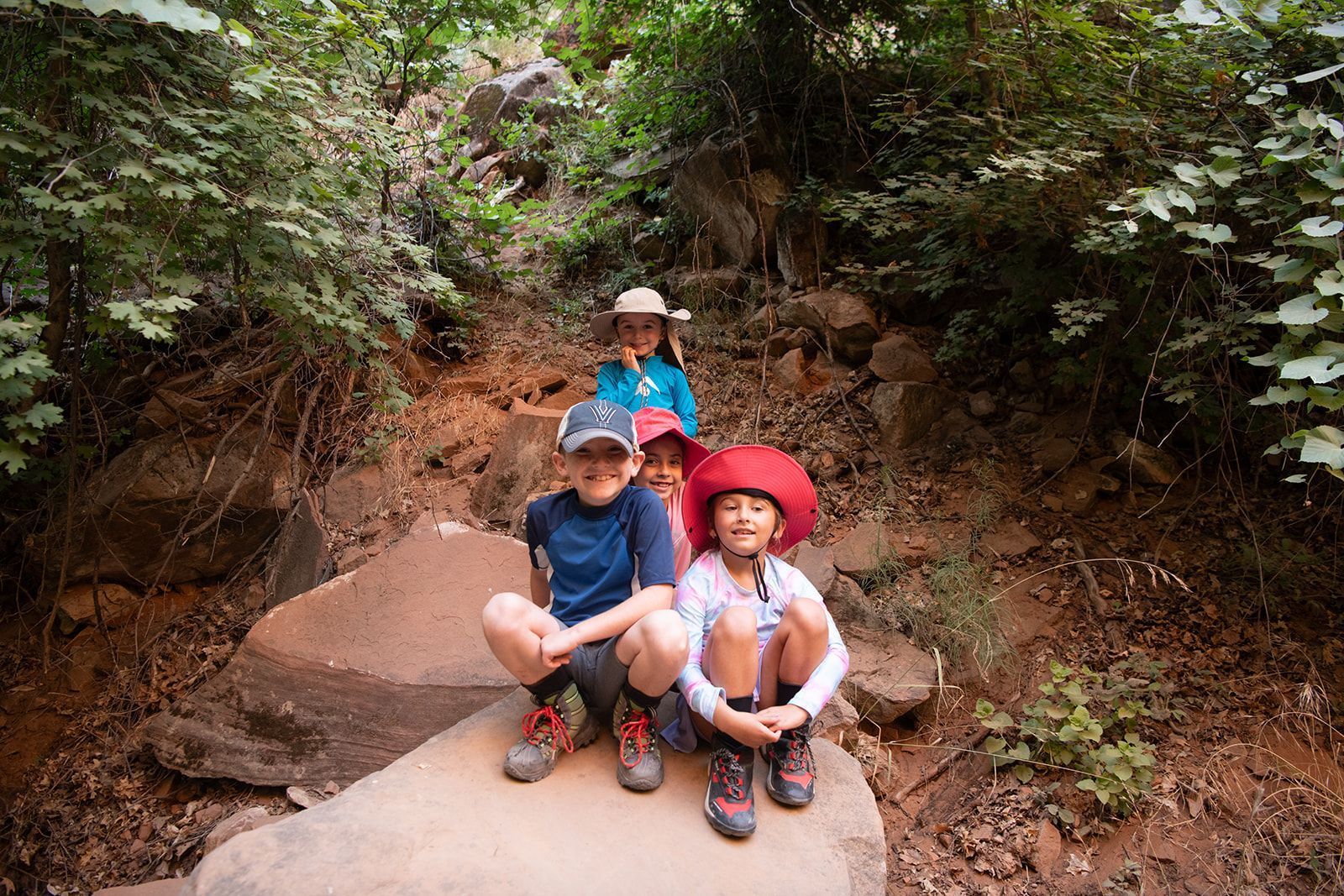 Smiling kids sitting on red rocks