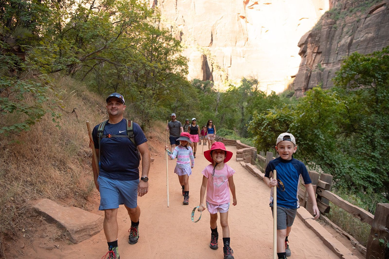 Kids walk along a path with walking sticks