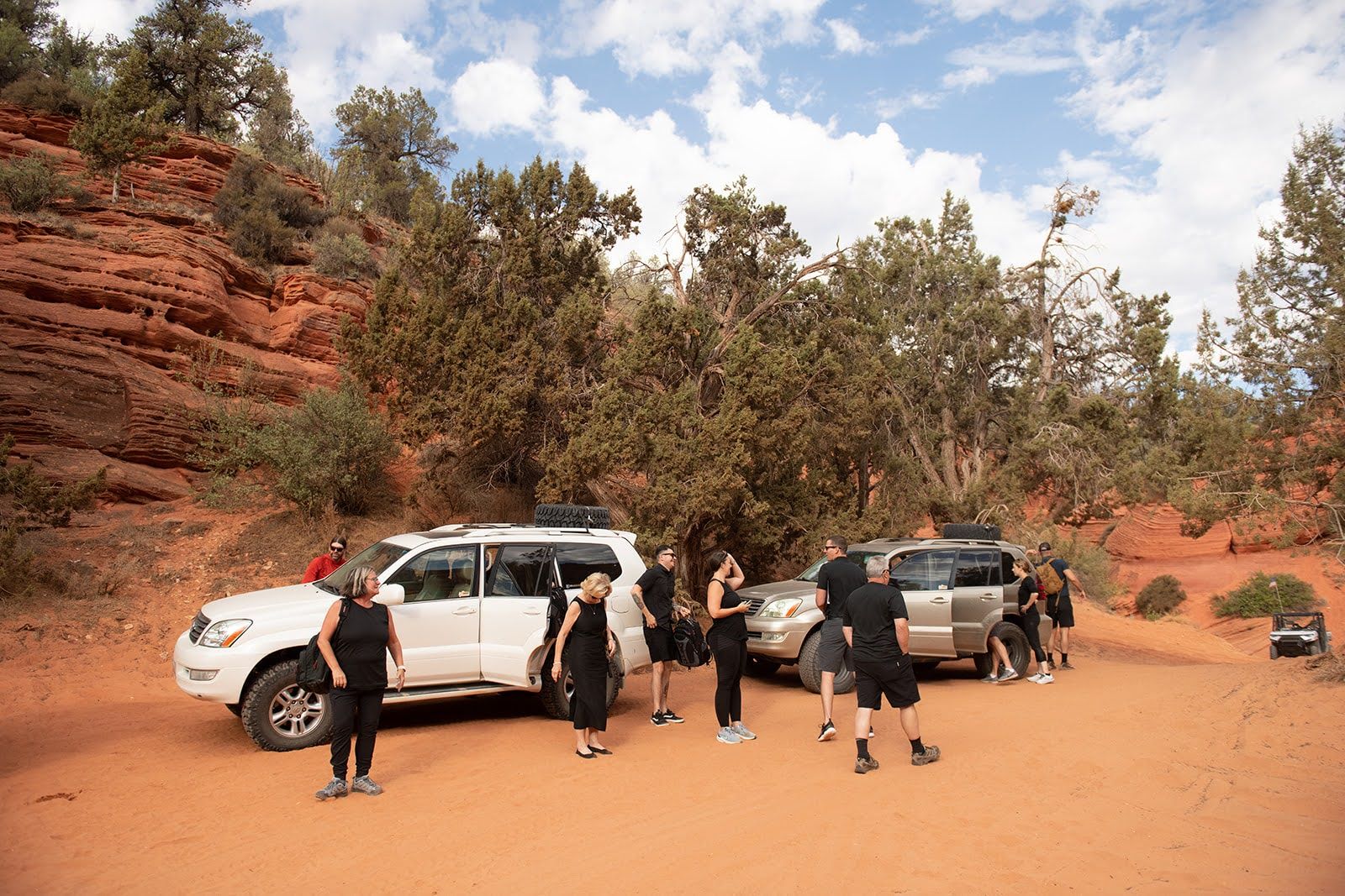 people getting ready to go to an elopement wedding, two cars and people in black 