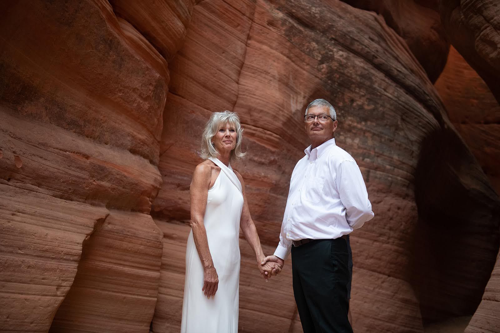 a man and woman holding hands in a canyon