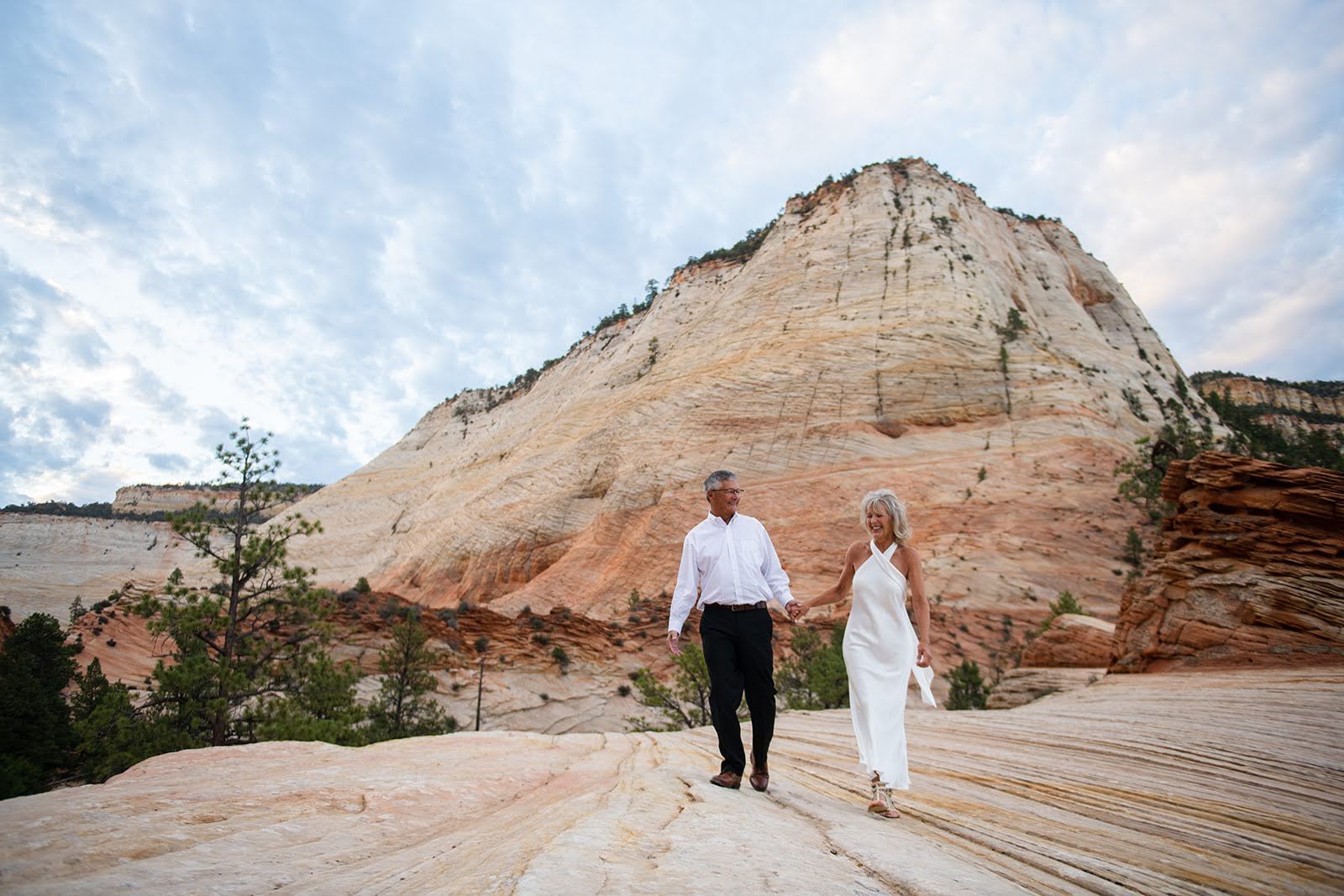 2 people holding hands in front of a mountain
