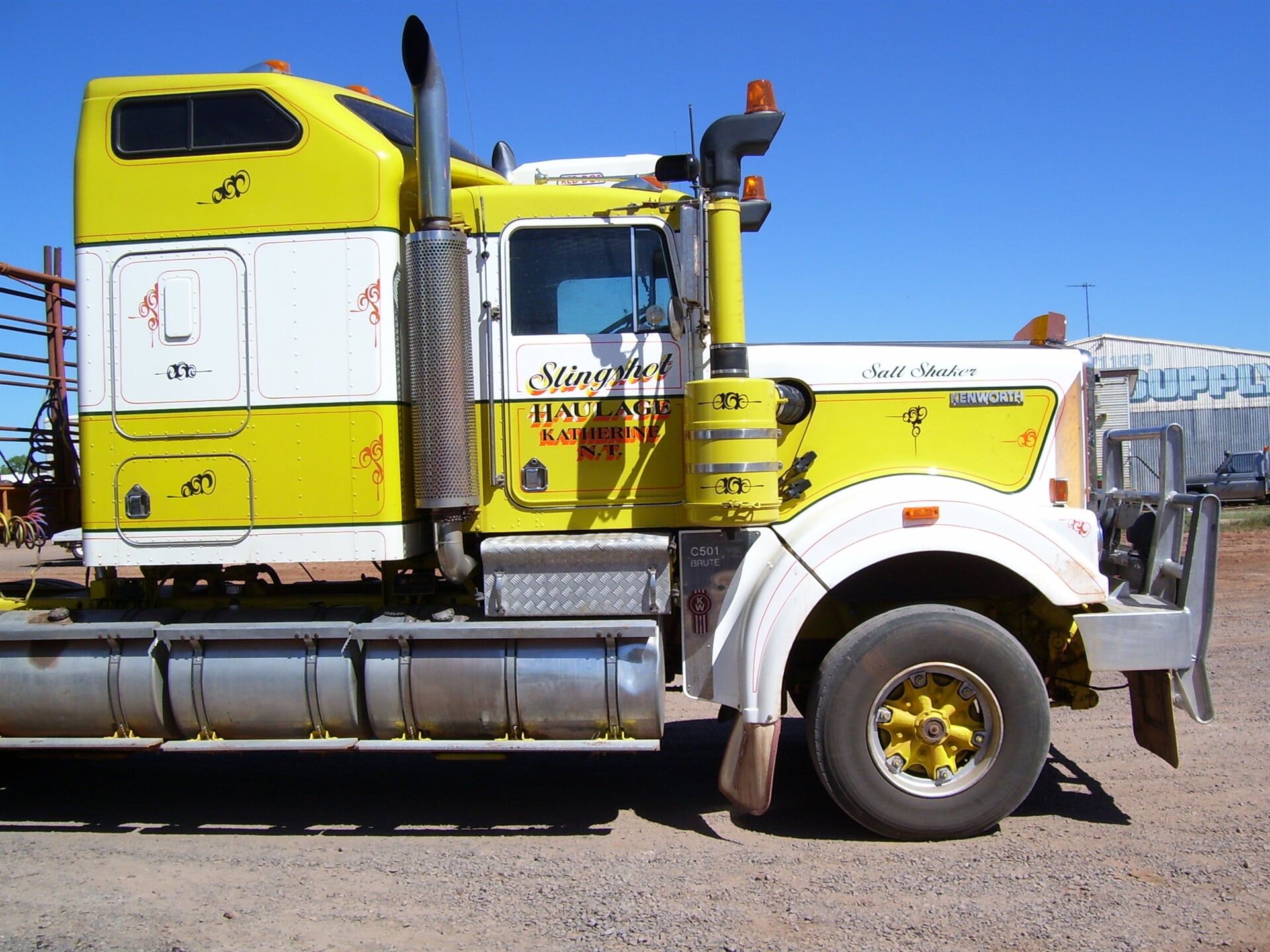 A yellow and white semi truck is parked on a dirt road- Slingshot Haulage in Katherine, NT