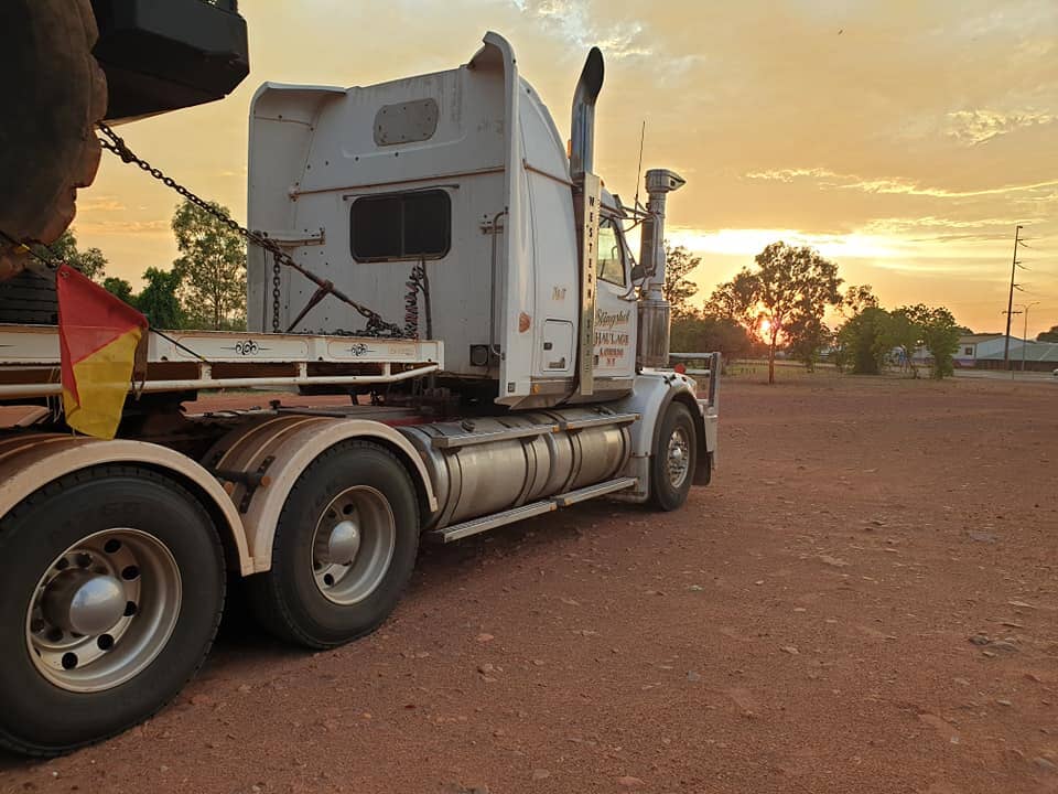 A semi truck is parked in a dirt lot at sunset- Slingshot Haulage in Katherine, NT