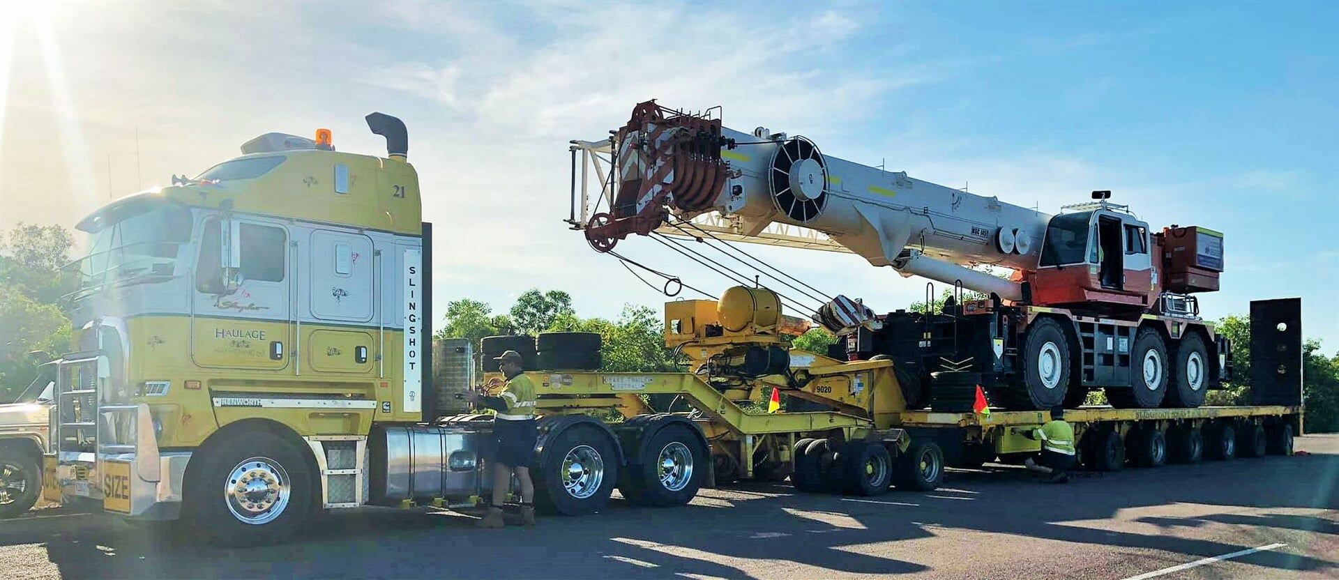 A large yellow truck with a crane on the back is parked on the side of the road- Slingshot Haulage in Katherine, NT