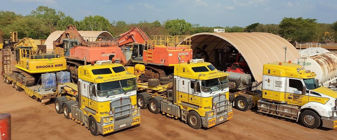 A group of yellow trucks are parked next to each other on a dirt road- Slingshot Haulage in Katherine, NT