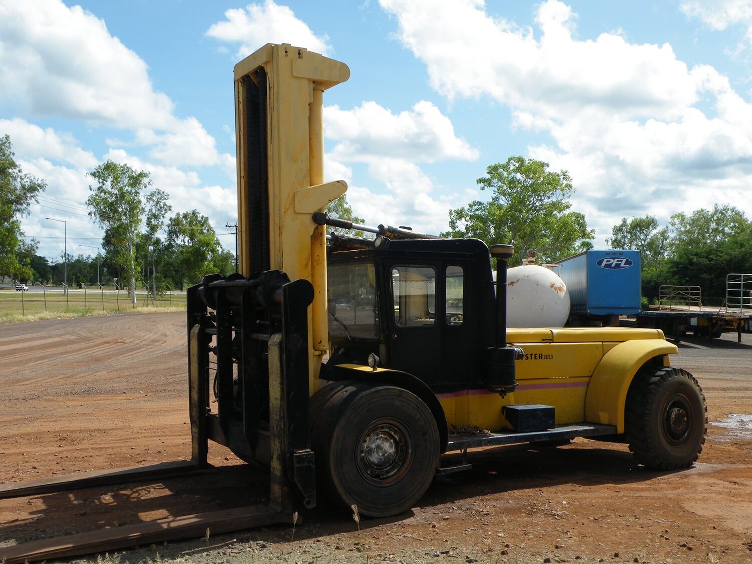 A large yellow forklift is parked in a dirt lot- Slingshot Haulage in Katherine, NT