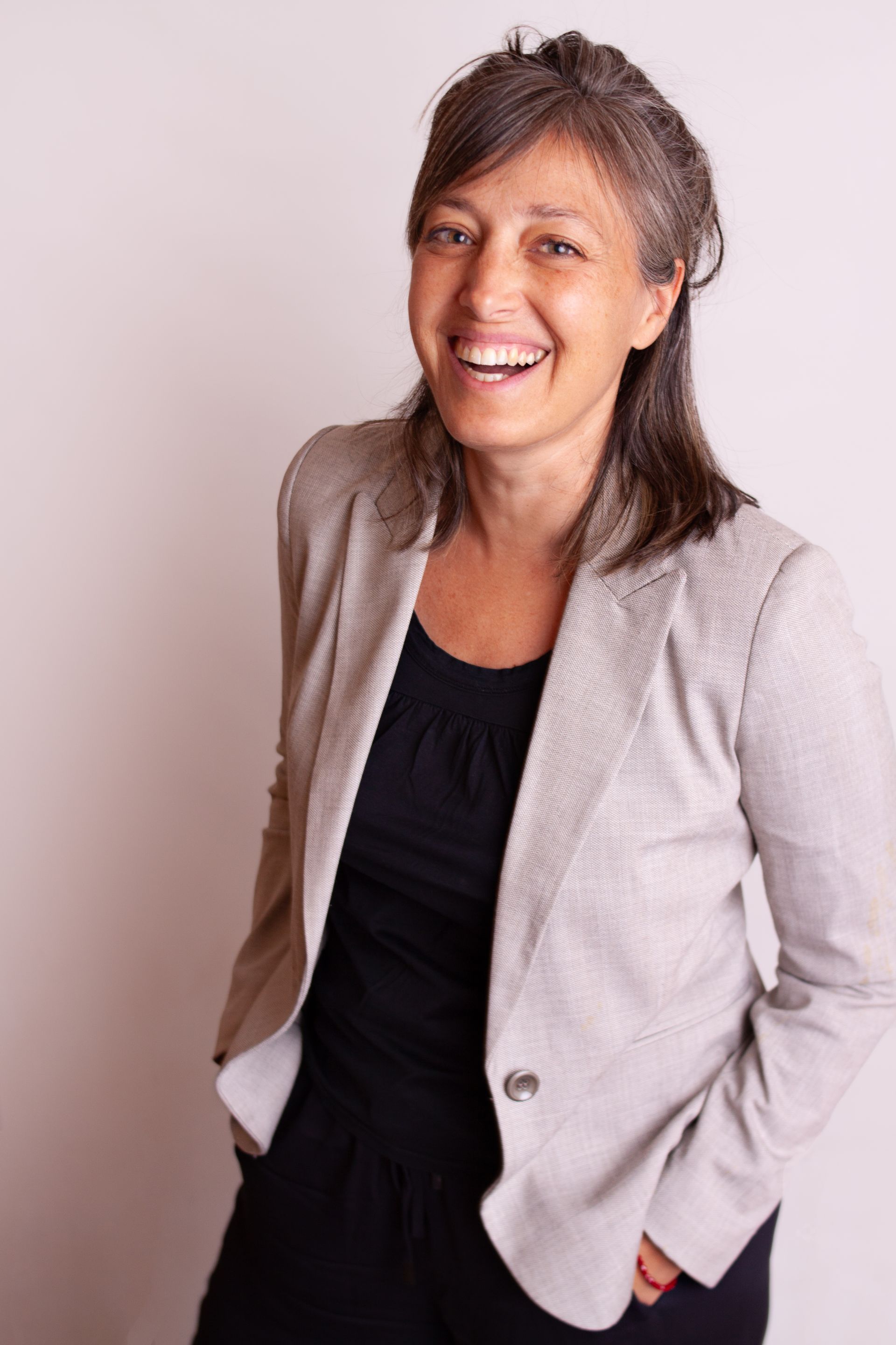 Una mujer que lleva una chaqueta gris y un vestido negro está sonriendo.