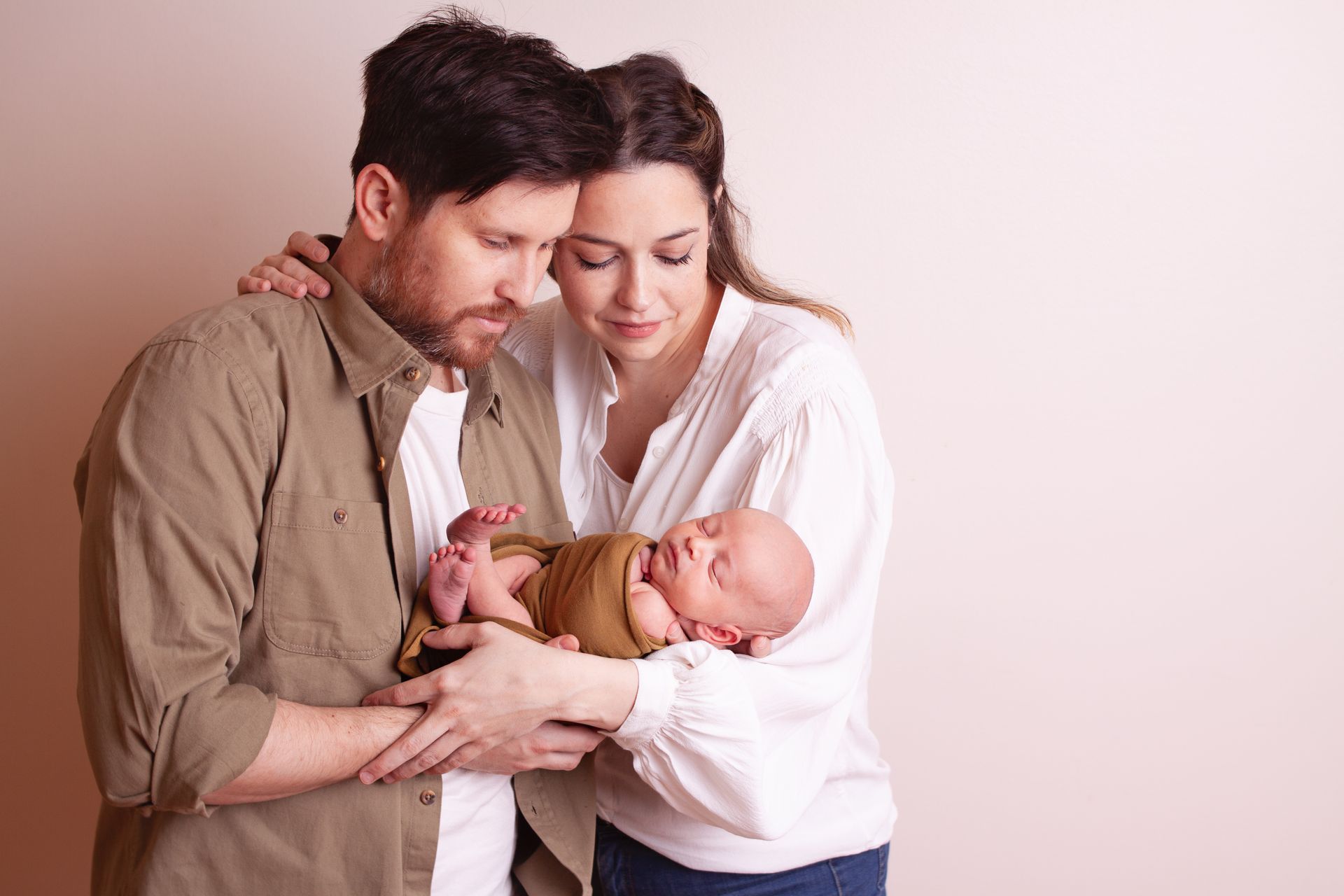 Un hombre y una mujer sostienen un bebé recién nacido en sus brazos.